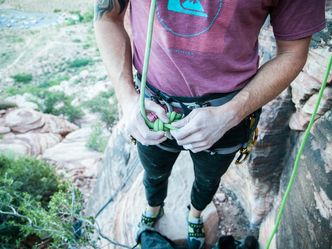 Which sport involves a controlled descent off a vertical drop while attached to a rope?