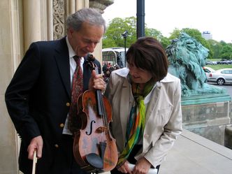 Which string instrument is the lady inspecting?