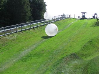 Which sport involves rolling down a hill inside an inflatable ball?